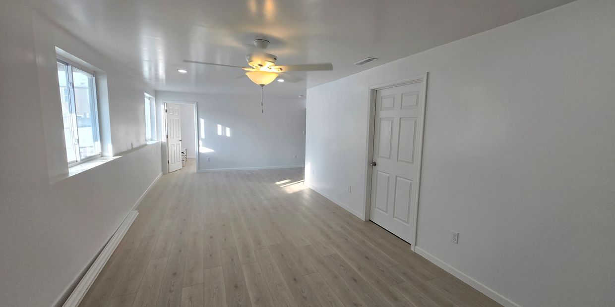 Bright, empty room with light wood flooring and white walls.