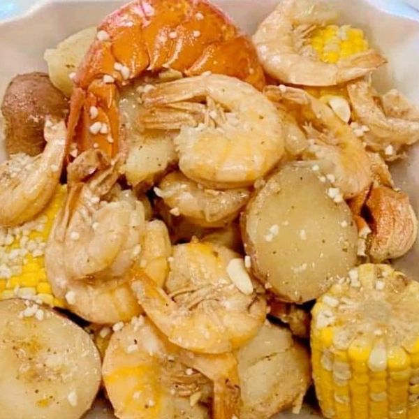 A close-up of a shrimp boil with potatoes and corn on the cob.