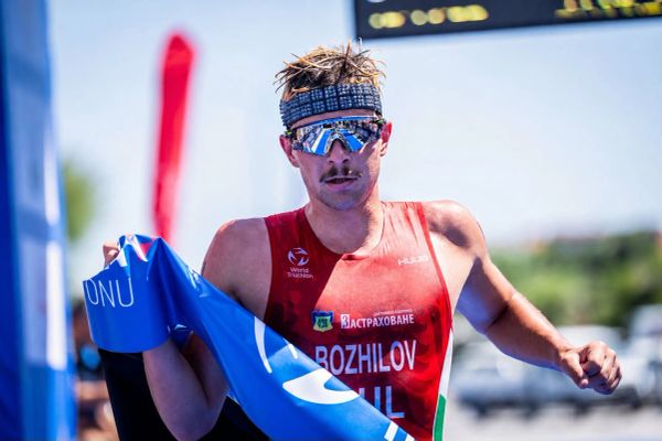 Athlete celebrating at a triathlon finish line.