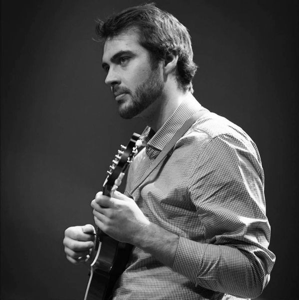 Man deeply focused playing an acoustic guitar in black and white.