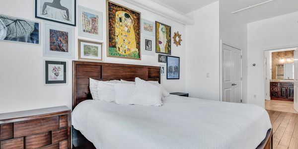 Bright bedroom with wooden furniture and framed artwork above the bed.