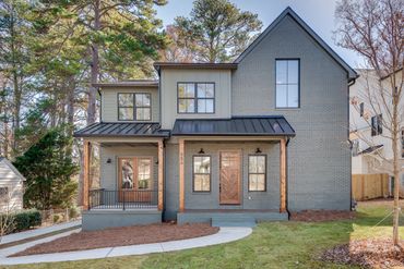 Modern two-story house with gray brick exterior and wooden accents.