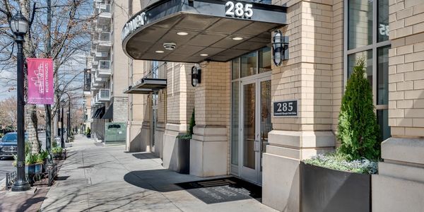 Entrance of a modern building at 285 with planters and street view.