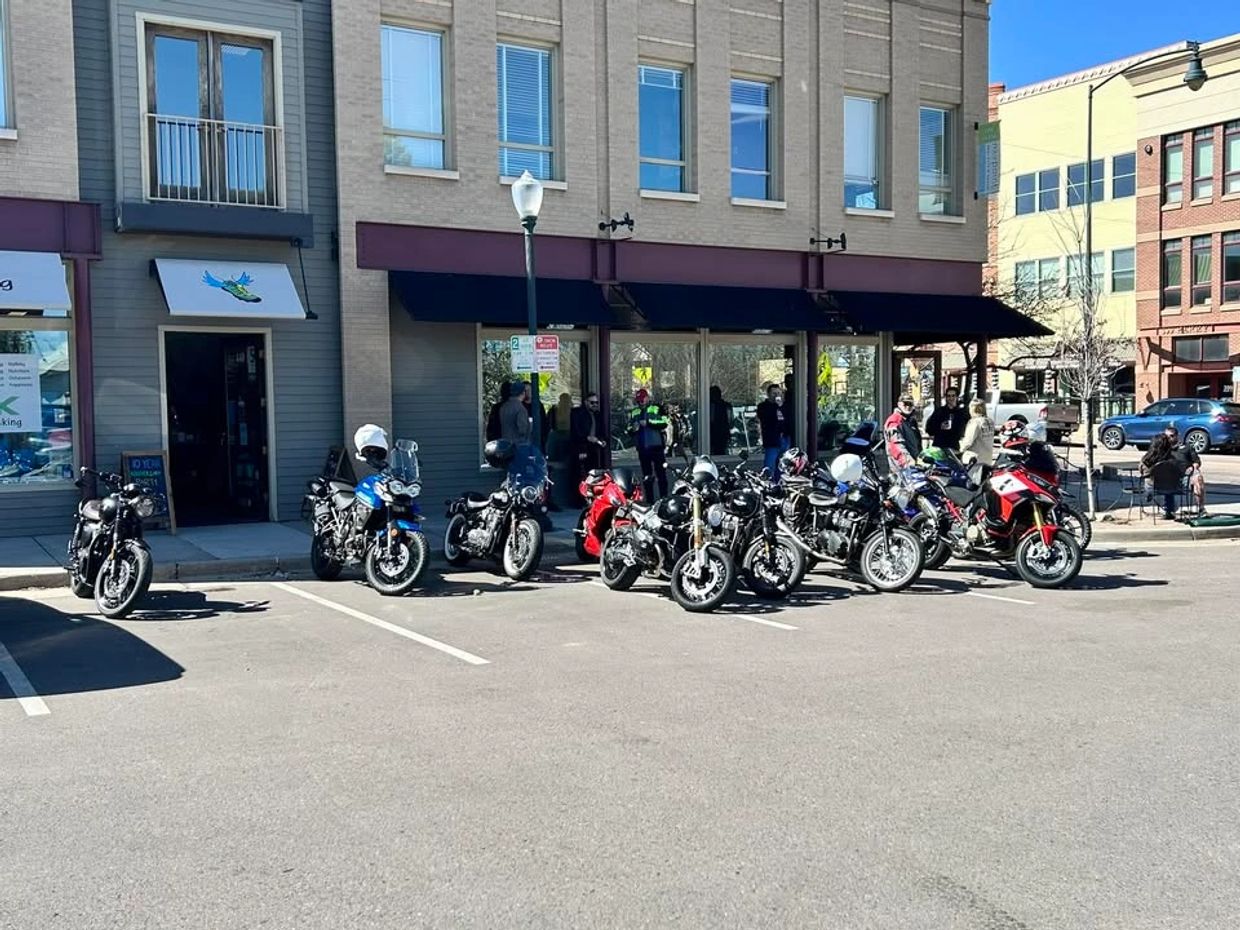 A group of motorcycles parked in front of a building on a sunny day.