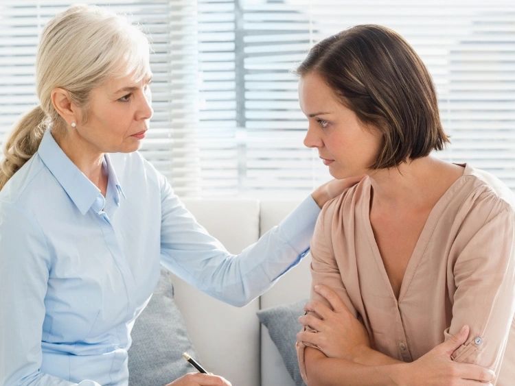 Grief counselor helping patient in therapist office in Denver.