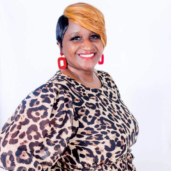 Smiling woman with stylish short hair and leopard print dress.