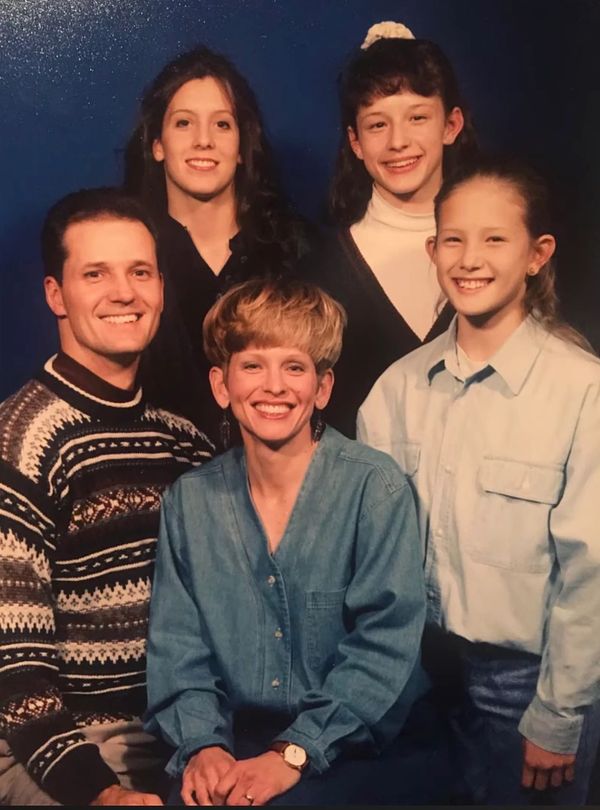 A smiling family of five posing against a blue backdrop.