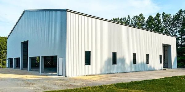 Large white metal warehouse building with multiple entrances and windows.