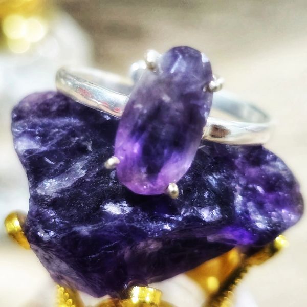Silver ring with a purple gemstone on a larger purple crystal.