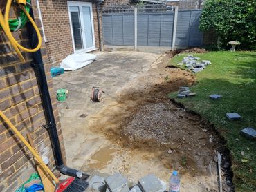 Partially dug up garden patio with paving stones and tools scattered around.