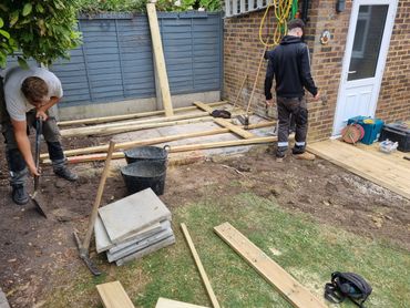 Two men working on a backyard wooden deck construction project.