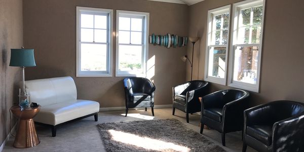 Office waiting room with tan walls, brown leather chairs and teal accent decor on walls