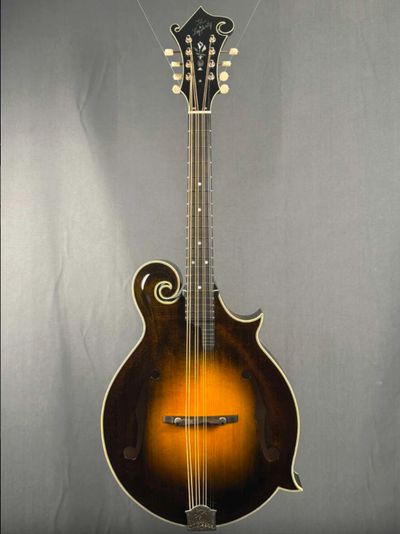 A sunburst F-style mandolin with intricate scroll design and tuning pegs.