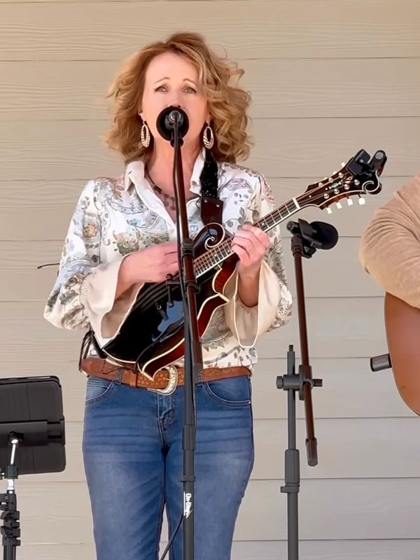 Woman playing mandolin and singing into a microphone.