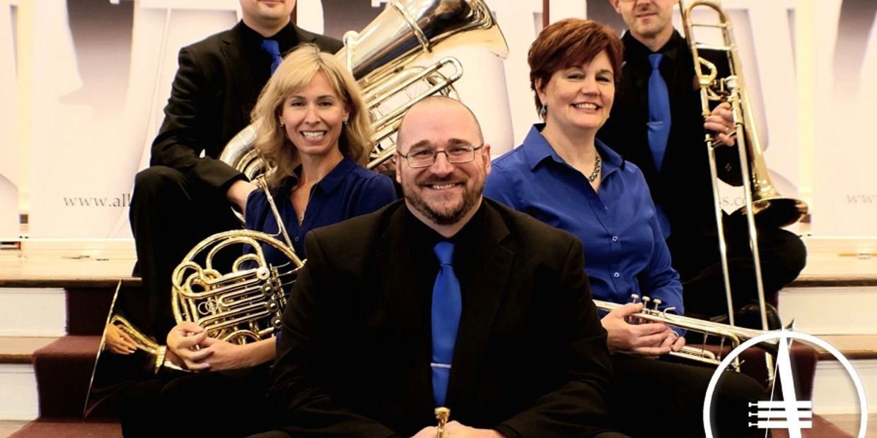 A group of musicians in formal attire posing with brass instruments.