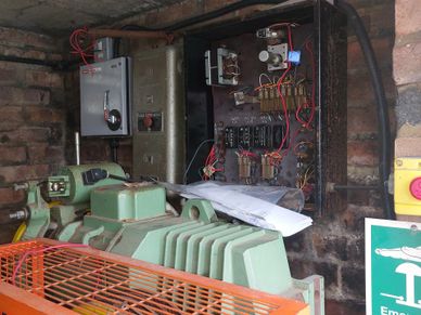 An industrial machine with an open electrical control panel showing wires and components.