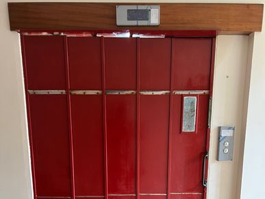 Red metal elevator doors with control panel on the right side.