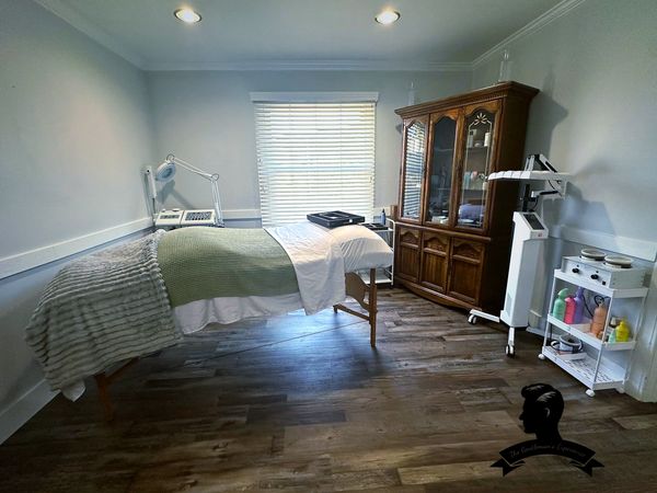 A cozy spa room with a massage table and wooden cabinet.