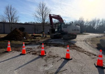 Excavator working at a construction site with traffic cones.