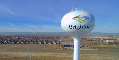 Water tower with Brighton logo against clear blue sky.