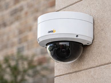 White dome security camera mounted on a beige wall.