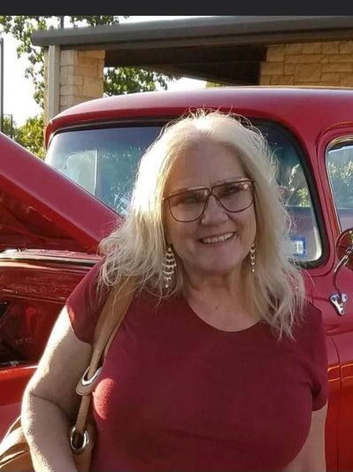 A smiling woman in front of a red pickup truck