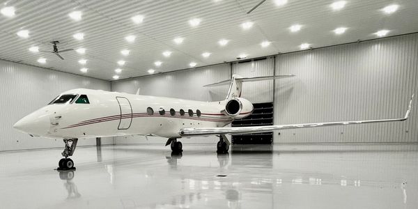 A sleek white private jet parked inside a well-lit hangar.