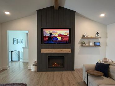 Cozy living room with fireplace and TV mounted on dark accent wall.