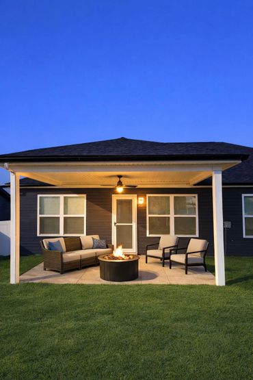 Cozy backyard patio with fire pit and seating under a covered porch at dusk.