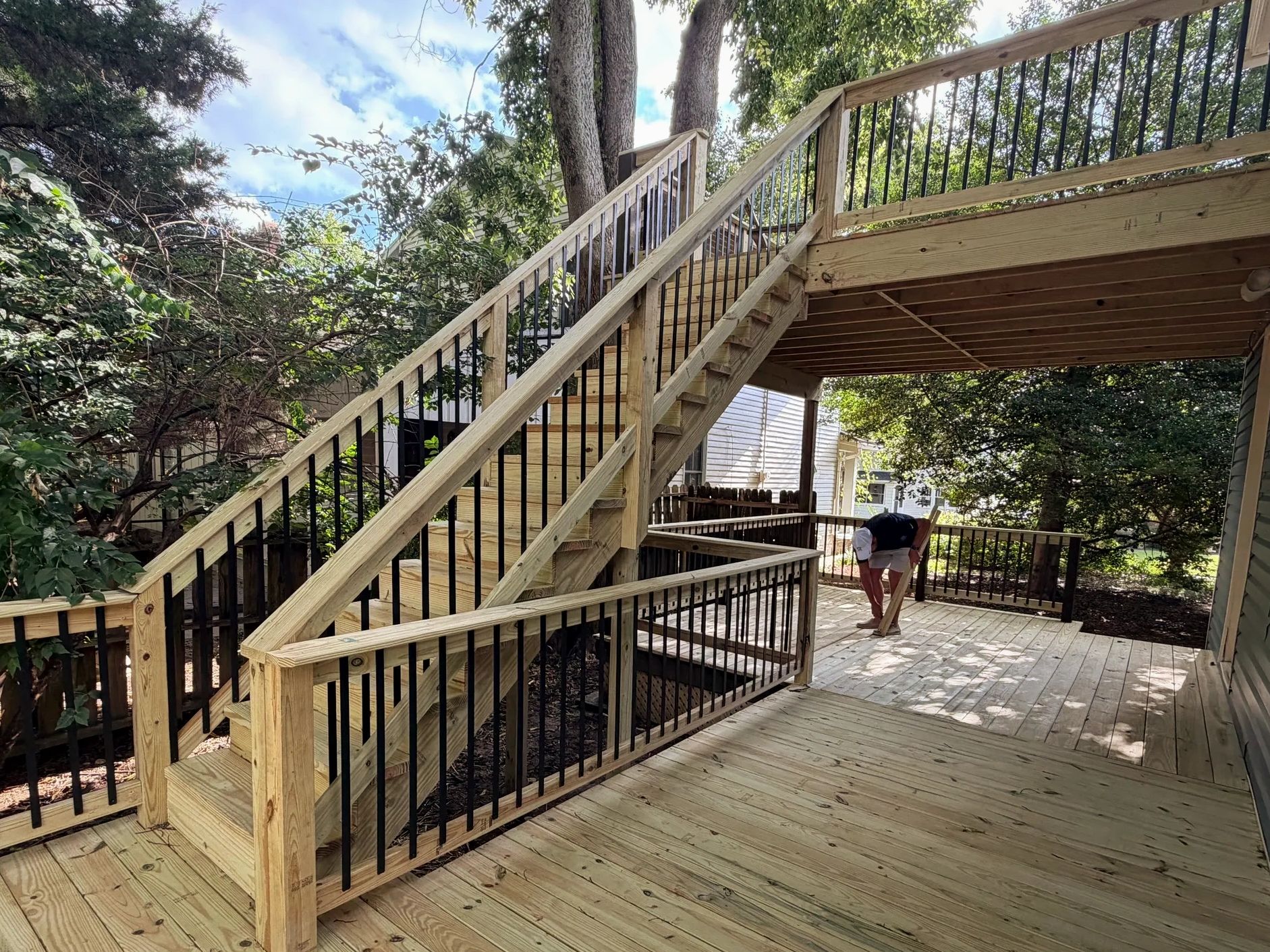 New wooden staircase and deck with black railing.