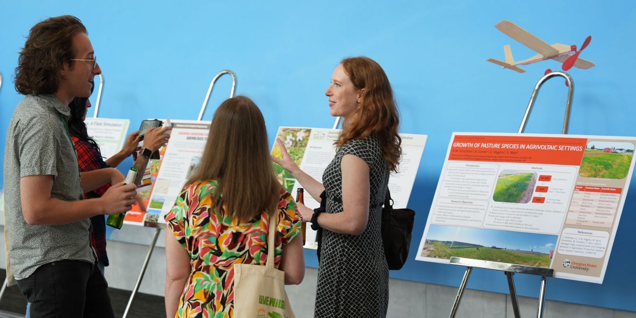 People discussing scientific posters at a conference with a model airplane overhead.