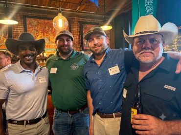 Four men posing together in a casual setting.