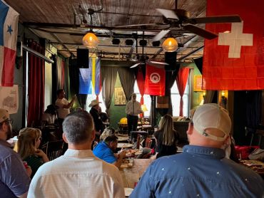 A group listening to a speaker in a room with flags.