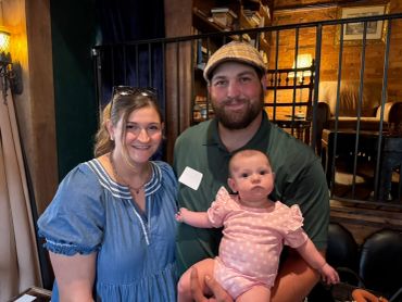 Family smiling with their baby in a cozy restaurant.