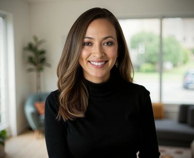 Smiling woman in a black turtleneck in a cozy living room.