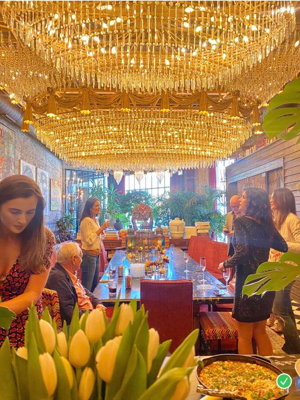 Elegant gathering under a grand chandelier in a cozy, art-filled dining space.