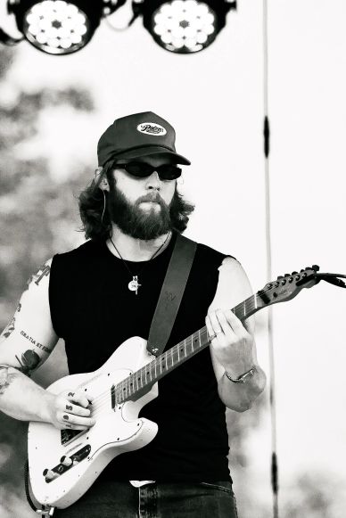 Bearded man playing electric guitar on stage.