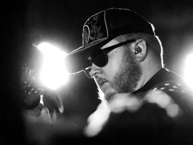 Black and white photo of a man wearing sunglasses and a cap.