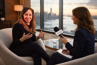 Two women engaged in an interview with a city skyline at sunset.