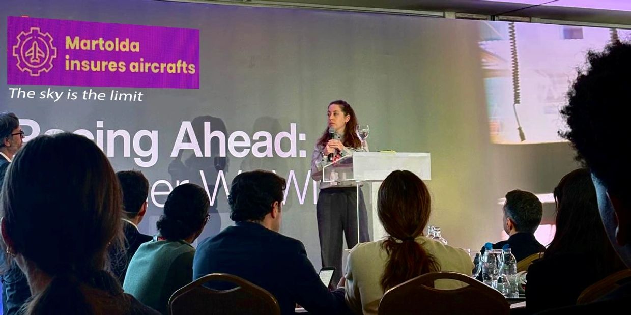 A woman speaks at a conference about aircraft insurance to an attentive audience.