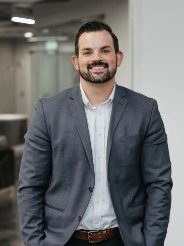 Smiling man in a gray suit jacket.