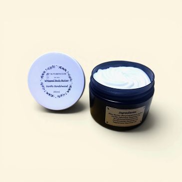Open jar of whipped body butter with lid beside it on a light background.
