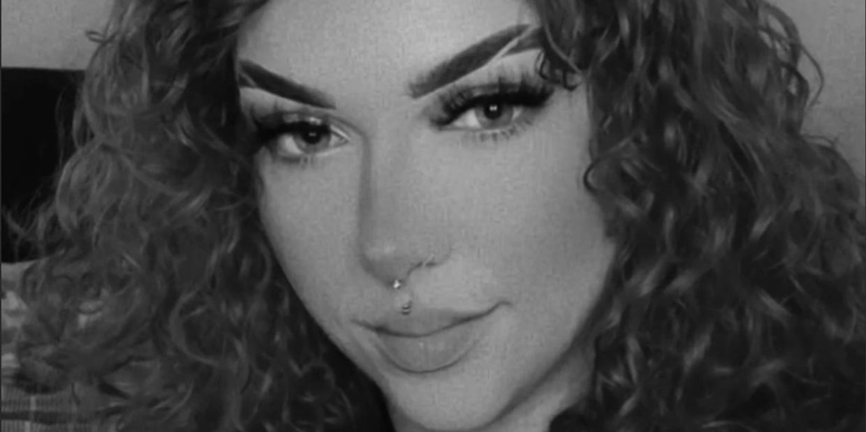 Close-up black and white portrait of a curly-haired woman with a septum piercing.