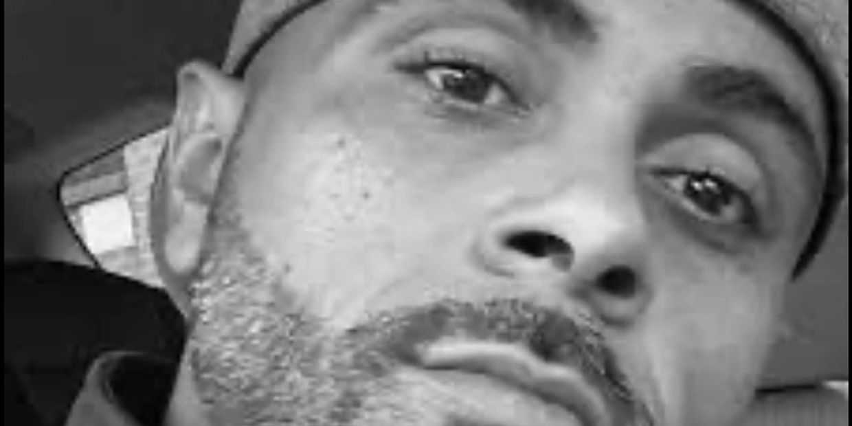 Close-up black and white portrait of a man wearing a cap.