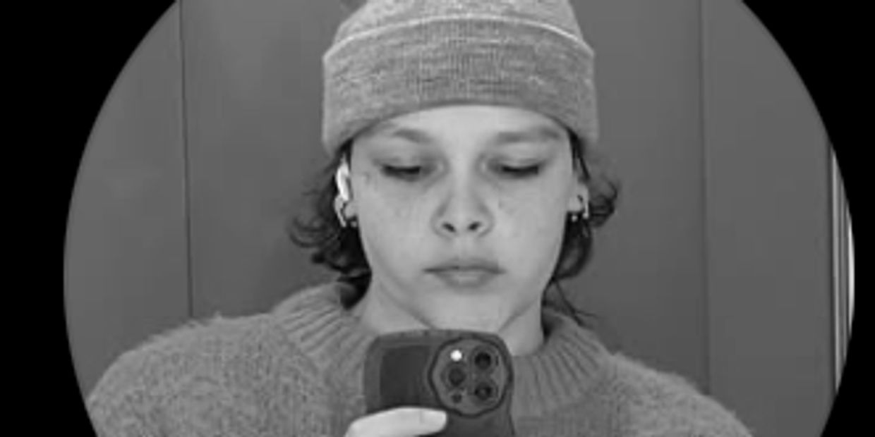 Black and white selfie of a person wearing a beanie and sweater.