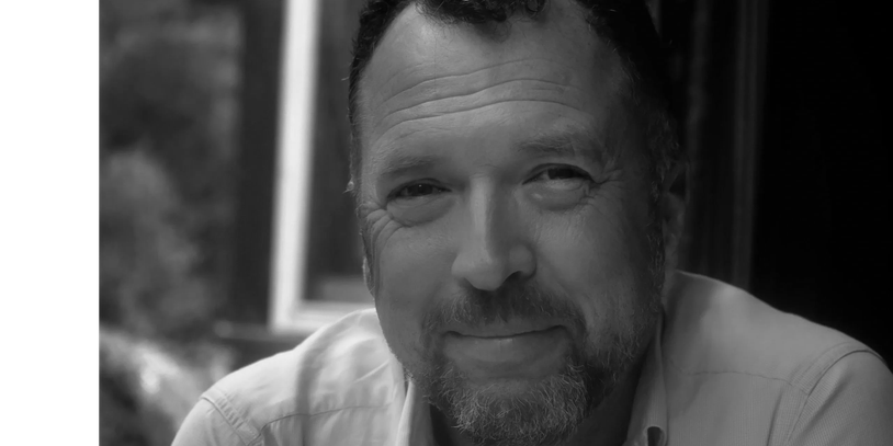 Black and white portrait of a smiling man.
