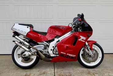 Red Suzuki sport motorcycle parked in front of a garage door.