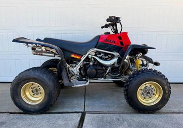 A red and black Yamaha all-terrain quad bike parked on pavement.