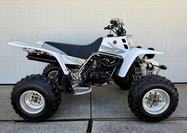 White Honda ATV with large off-road tires parked on driveway.
