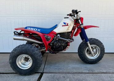 A red and white 350X three-wheeled off-road vehicle with large tires.